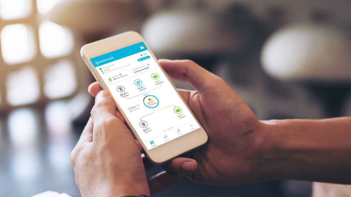 homeowner holding phone using solar panel monitoring app to track solar panel production